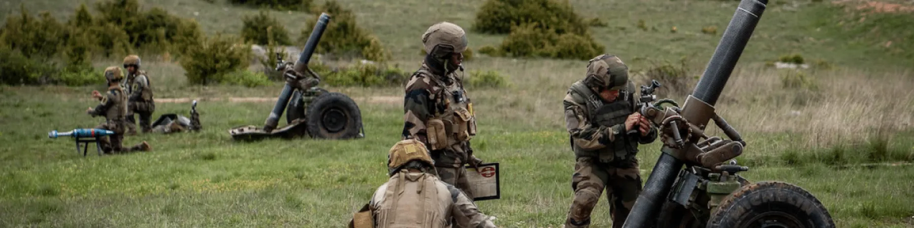 Legionários da 13.ª Demi‑Brigada da Legião Estrangeira a operar um morteiro pesado de 120 mm num campo de instrução ao ar livre.